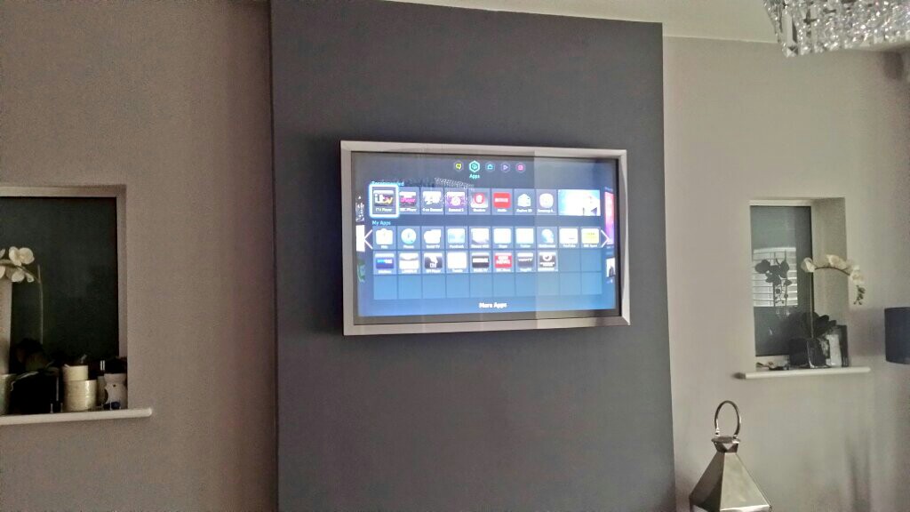 Mirror TV switched on showing the television picture in a home interior